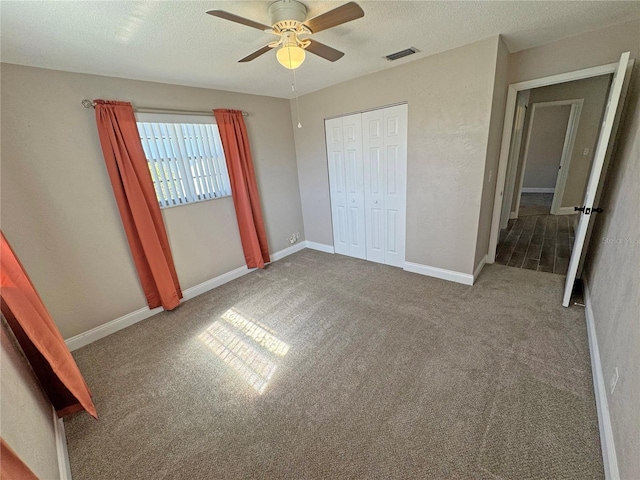 unfurnished bedroom featuring visible vents, a textured ceiling, a closet, carpet floors, and baseboards