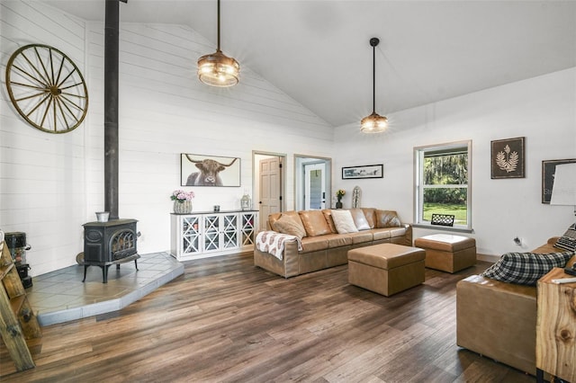 living room with high vaulted ceiling, wood finished floors, and a wood stove