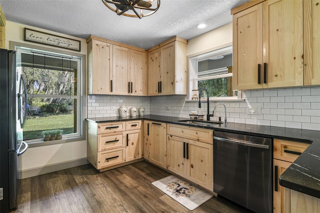 kitchen featuring dark countertops, a sink, dishwasher, and freestanding refrigerator