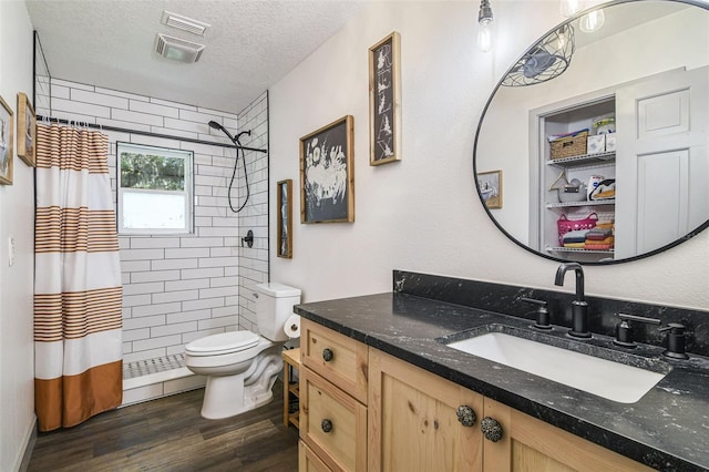 full bathroom with wood finished floors, toilet, vanity, a shower stall, and a textured ceiling