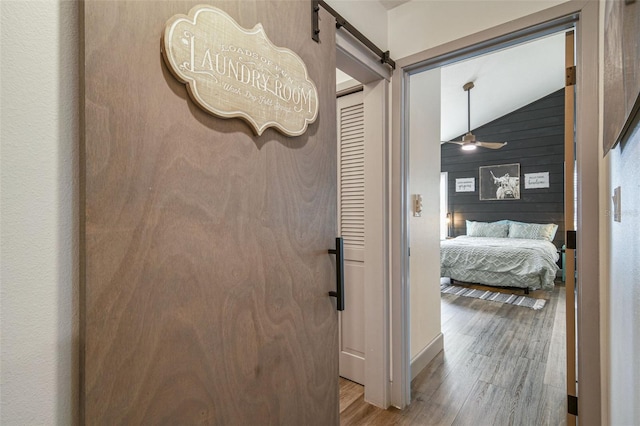 corridor with light wood-style floors, wood walls, and a barn door