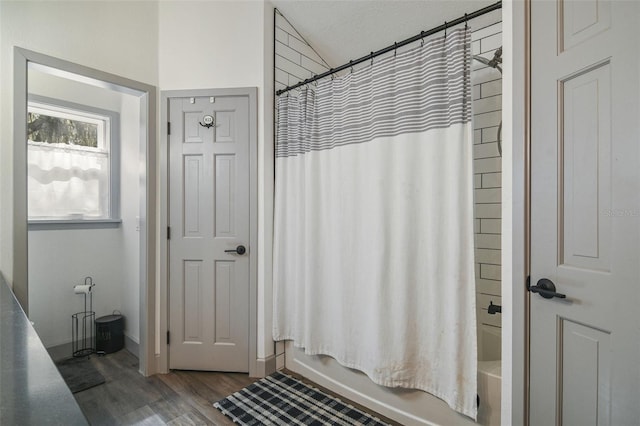 bathroom with shower / bathtub combination with curtain and wood finished floors