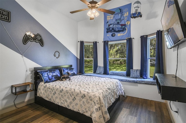 bedroom featuring dark wood-style floors, ceiling fan, and a towering ceiling