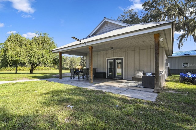 rear view of house featuring french doors, a patio, metal roof, and a lawn