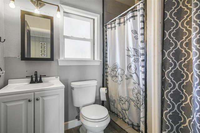 full bathroom with toilet, a shower with curtain, baseboards, and vanity