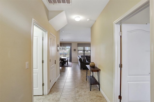 corridor featuring an inviting chandelier and light tile patterned floors