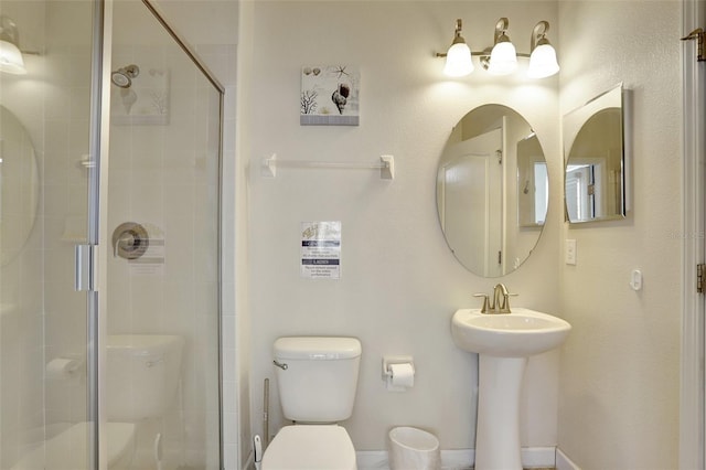 bathroom with a shower with door, sink, and toilet