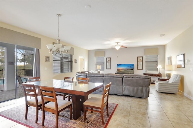 tiled dining room with ceiling fan with notable chandelier