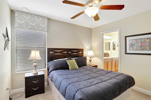 bedroom with ceiling fan, light colored carpet, and connected bathroom