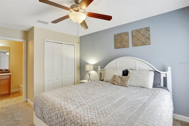 bedroom with ceiling fan, light colored carpet, and a closet