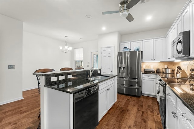 231 Turtle Cv, Panama City Beach, FL 32413 - kitchen featuring a breakfast bar, sink, black appliances, dark stone counters, and white cabinets