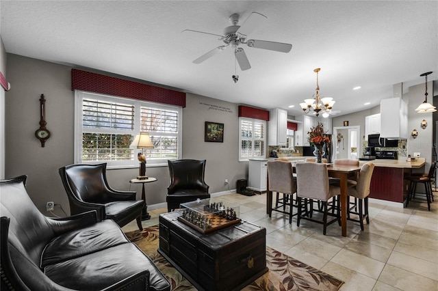 tiled living room with ceiling fan with notable chandelier