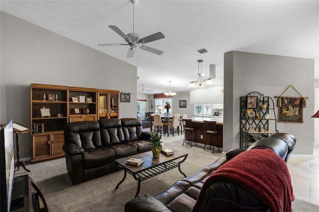 carpeted living room featuring ceiling fan with notable chandelier, vaulted ceiling, and a textured ceiling