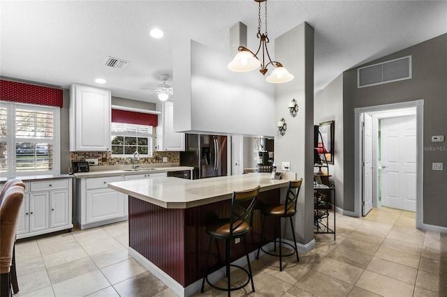 kitchen featuring stainless steel fridge with ice dispenser, sink, a breakfast bar area, white cabinets, and kitchen peninsula