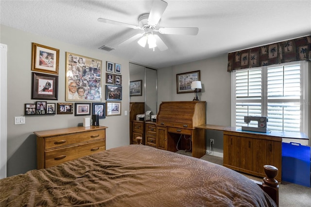 carpeted bedroom featuring ceiling fan and a textured ceiling