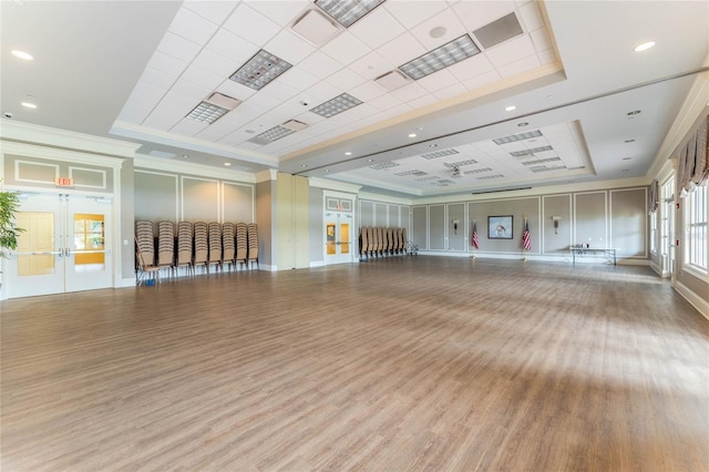 workout area featuring french doors, ornamental molding, a raised ceiling, and hardwood / wood-style floors