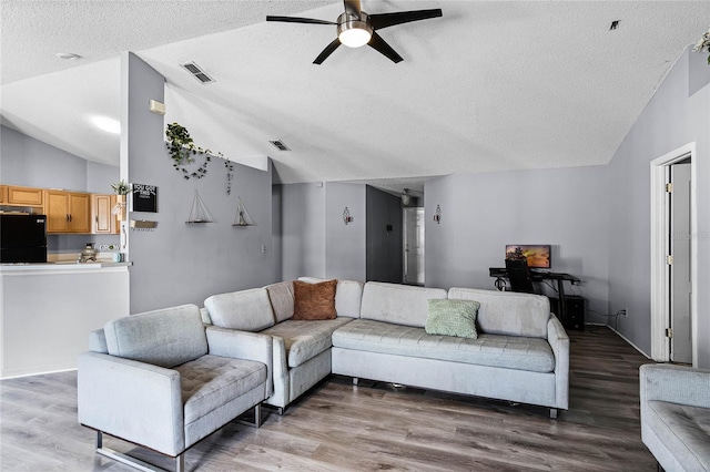 living room featuring wood-type flooring, lofted ceiling, a textured ceiling, and ceiling fan