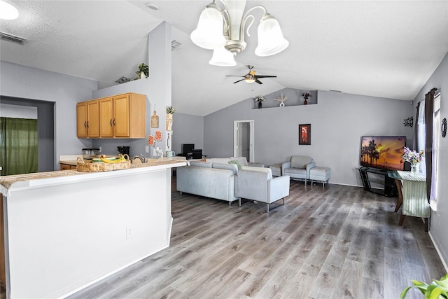 kitchen with lofted ceiling, light brown cabinets, kitchen peninsula, ceiling fan, and hardwood / wood-style floors