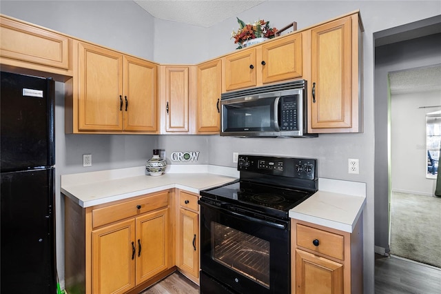 kitchen with light hardwood / wood-style flooring, light brown cabinetry, a textured ceiling, and black appliances