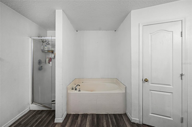 bathroom with shower with separate bathtub, hardwood / wood-style floors, and a textured ceiling