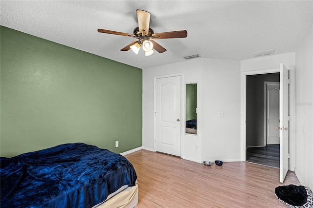 bedroom featuring wood-type flooring, ceiling fan, and a textured ceiling