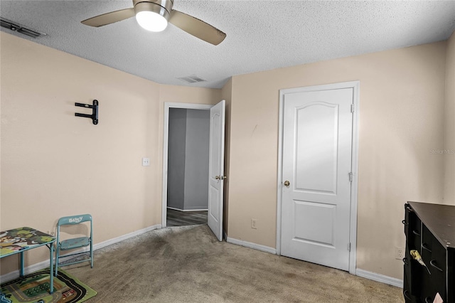 interior space featuring ceiling fan, carpet floors, and a textured ceiling