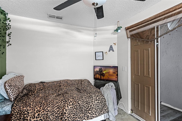 carpeted bedroom with ceiling fan and a textured ceiling