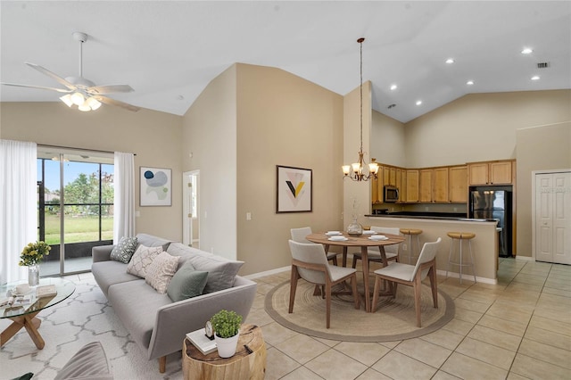 tiled dining room with ceiling fan with notable chandelier and high vaulted ceiling