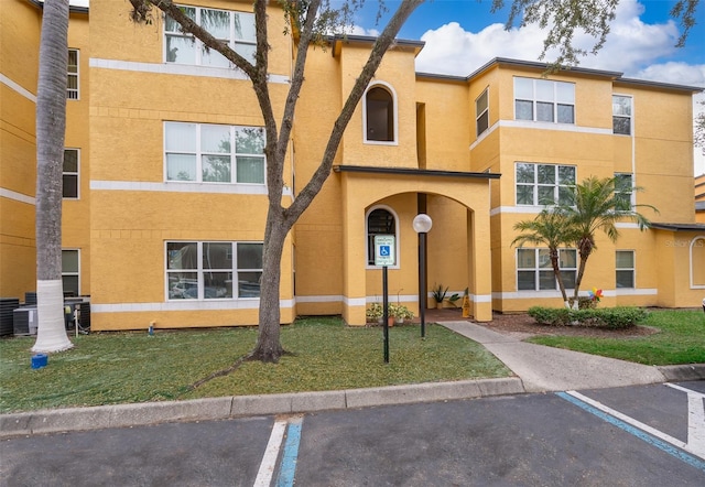 view of property with central AC unit and uncovered parking