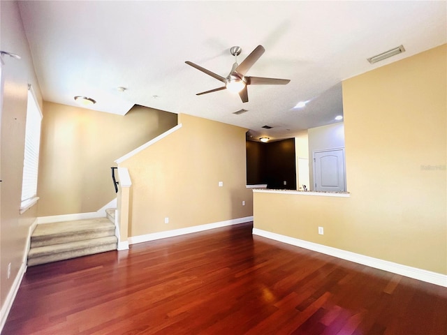 unfurnished living room featuring dark wood-type flooring and ceiling fan