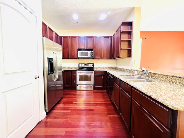 kitchen with appliances with stainless steel finishes, kitchen peninsula, sink, and light stone countertops