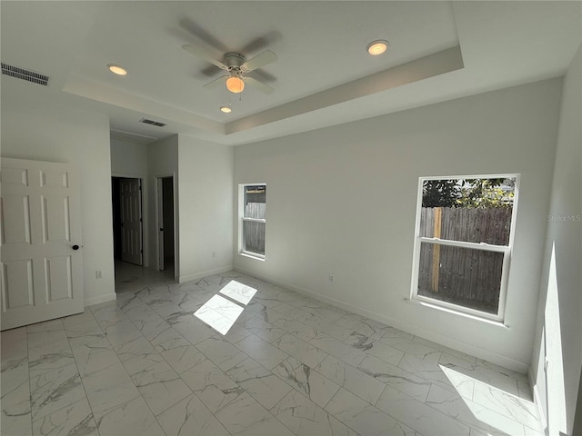 spare room featuring ceiling fan and a tray ceiling