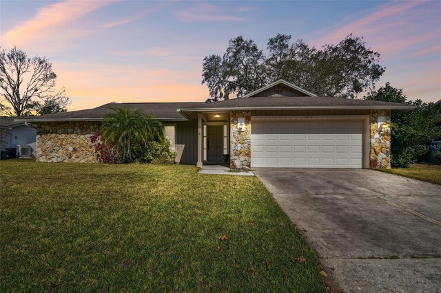 ranch-style home with a garage and a lawn