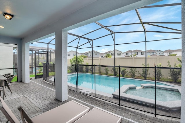 view of pool featuring an in ground hot tub, glass enclosure, and a patio