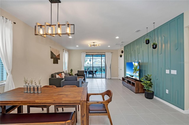 dining space featuring an inviting chandelier, wood walls, and light tile patterned floors