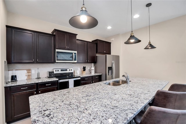 kitchen with stainless steel appliances, a kitchen bar, sink, and hanging light fixtures