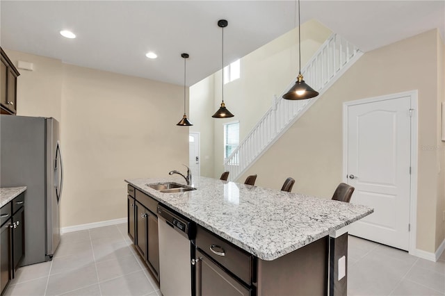 kitchen featuring pendant lighting, an island with sink, sink, dark brown cabinetry, and stainless steel appliances