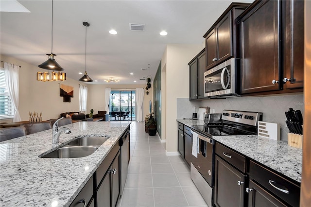 kitchen featuring sink, backsplash, hanging light fixtures, stainless steel appliances, and light stone countertops