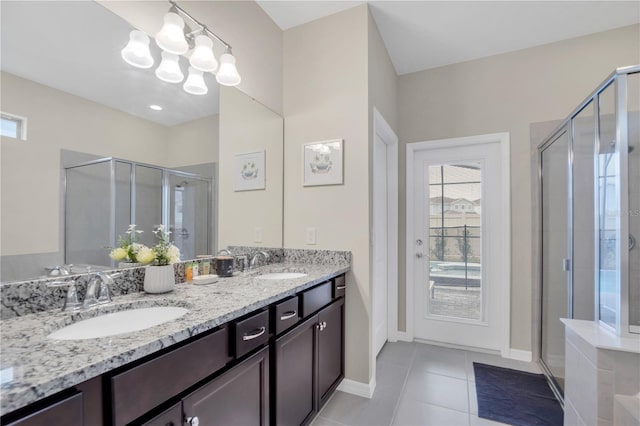 bathroom with a shower with door, vanity, tile patterned floors, and an inviting chandelier