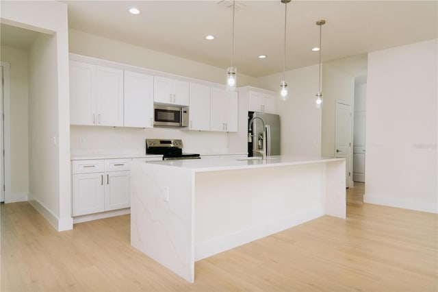 kitchen featuring light wood finished floors, light countertops, appliances with stainless steel finishes, white cabinetry, and a kitchen island with sink