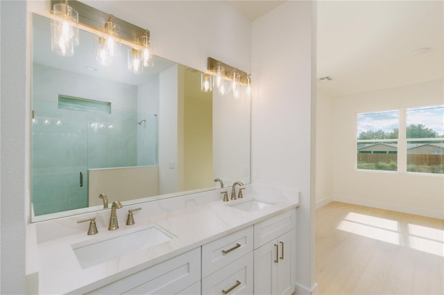 full bathroom with a sink, baseboards, a stall shower, and double vanity