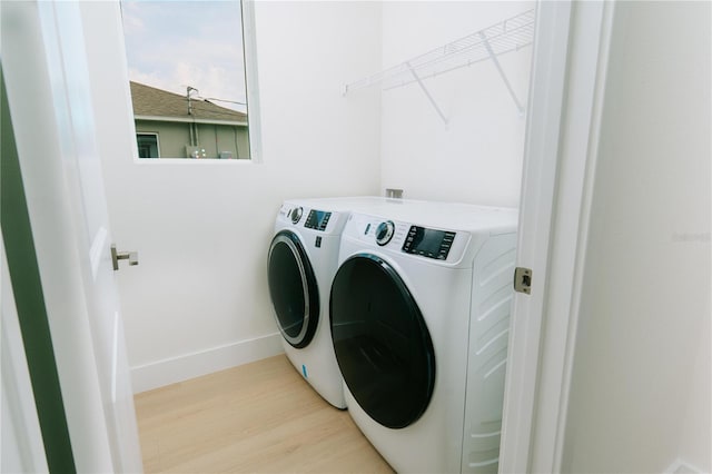 laundry room featuring light wood-style flooring, baseboards, washing machine and dryer, and laundry area