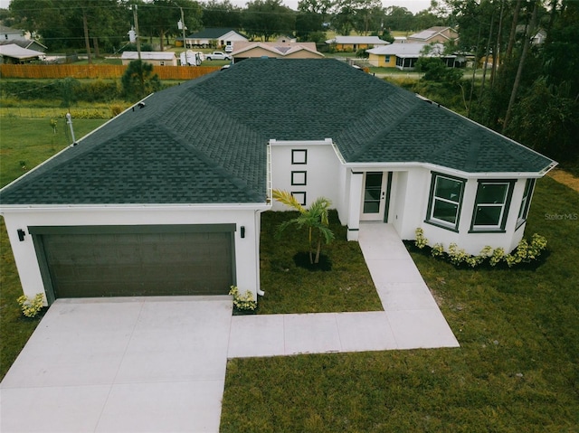 view of front facade featuring a front lawn, roof with shingles, stucco siding, driveway, and an attached garage