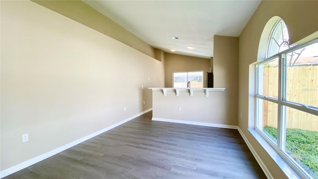 unfurnished room featuring dark wood-type flooring, a wealth of natural light, and baseboards