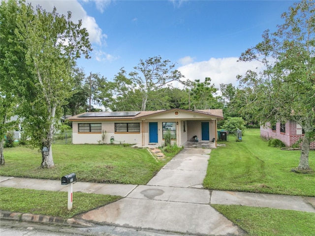 single story home with a front yard and solar panels