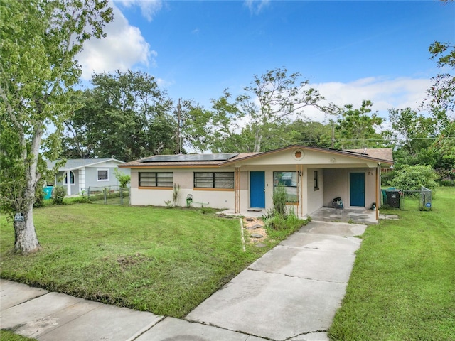 ranch-style house featuring a front yard and solar panels