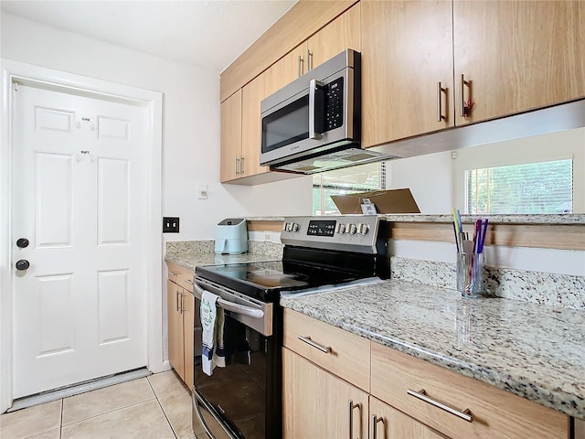 kitchen with light stone countertops, appliances with stainless steel finishes, light brown cabinets, and light tile patterned floors