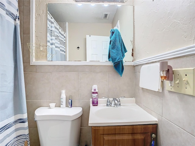 bathroom with vanity, tile walls, and toilet