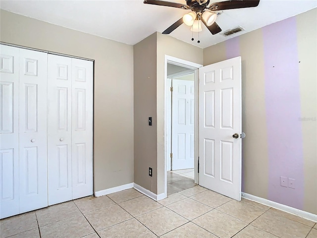 unfurnished bedroom with light tile patterned floors, ceiling fan, and a closet