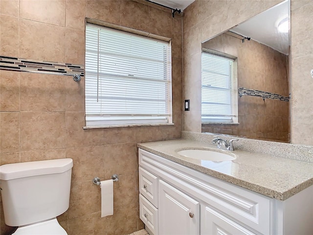 bathroom featuring vanity, toilet, and tile walls